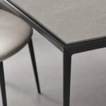 Detaliu generat al blatului ceramic gri și al îmbinării cadrului metalic
