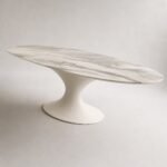 Masă de dining Nevia cu blat oval marmorat și soclu fluid, perspectivă alternativă generată
