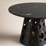 Detaliu generat al blatului mineral negru și soclului perforat cu interior bronz