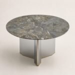 Masă de dining rotundă Triskel cu blat mineral gri-verde și soclu prismatic auriu, perspectivă alternativă generată