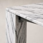 Detaliu generat al blatului marmorat alb, piciorului monolitic și rostului structural retras
