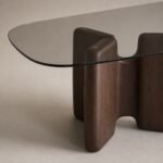 Detaliu generat al blatului din sticlă fumurie și soclului sculptural din lemn