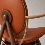 Detaliu generat al pielii cognac, cadrului din nuc și brațului din alamă înfășurat
