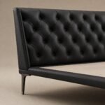 Detaliu generat al capitonării tip diamant, pielii negre și piciorului metalic conic